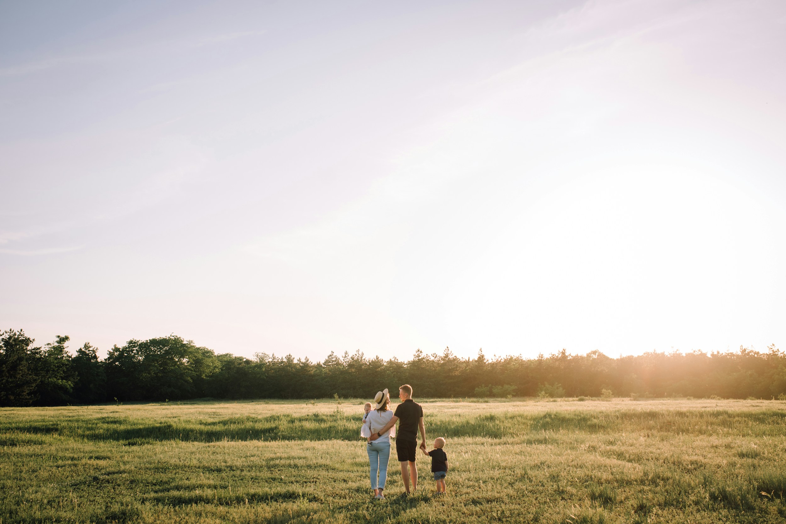 Family walking through a golden field at sunset